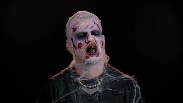 Sinister Man in Costume of Halloween Crazy Zombie with Bloody Wounded Scars Face Trying to Scare