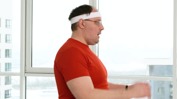 Funny Overweight Man Puts on Headband and Looking Into Camera