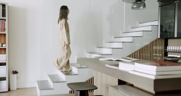 Slow Motion Shot of Young Caucasian Freelance Woman Walking Up Stairs in Home