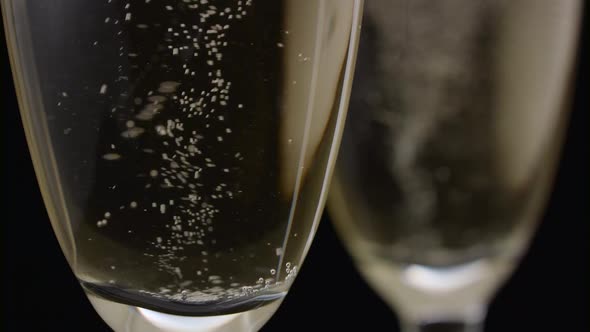 Glass of Champagne with a Rotating Bubbles Inside. Black Background. Close Up