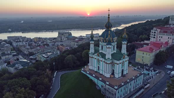 Kyiv, Ukraine. Flying Over St. Andrew's Church on the Bank of Dnieper River During Sunrise. Aerial