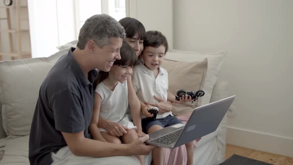 Cheerful Parents and Two Children with Laptop in Living Room