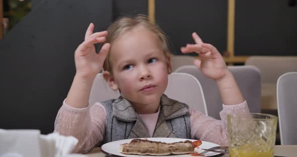 Closeup Portrait of Cute Caucasian Girl Grimacing Having Fun Eating Pizza in Restaurant