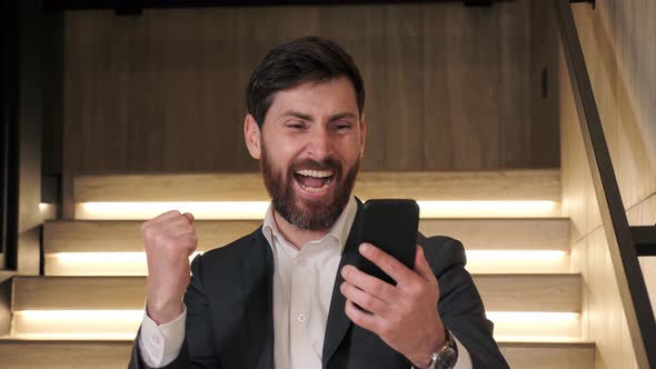 Happy Lucky Businessman Cheering Celebrating Looking at Cell Phone