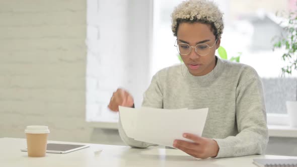 African Woman Reading Reports While Sitting in Office