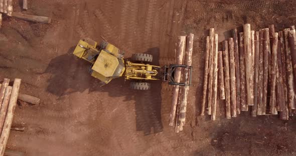 4K Aerial Top Down of Yellow Timber Front End Loader Vehicle With Claws Moving Logs