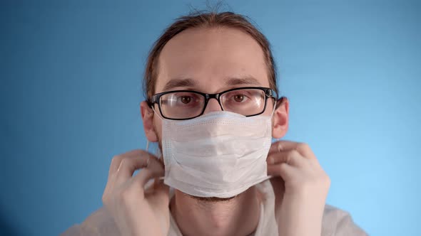 Man in Protective Jumpsuit Puts Medical Mask on Face Zips Jacket Puts on Hood