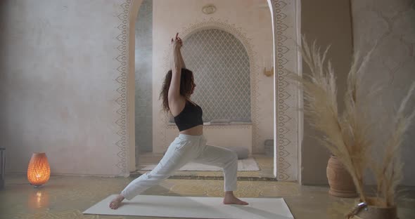 Sporty CurlyHaired Woman Does Yoga Stretching Exercises