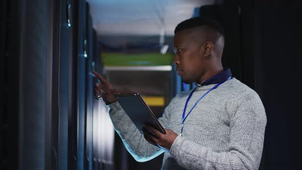 African american male computer technician using tablet working in business server room