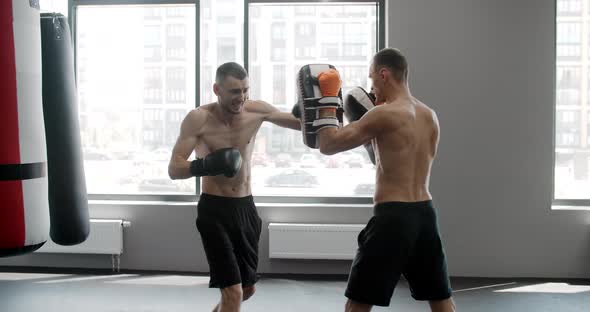 MMA Fighter is Practising His Strikes with Trainer in Slow Motion in the Gym Kickboxers are Training