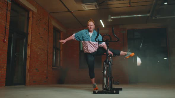 Athletic Woman Makes Twine Training Routine on Spinning Stationary Bike in Gym Stretching Exercises