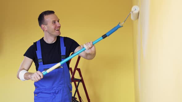 Young man painting wall with roller brush while renovating his apartment