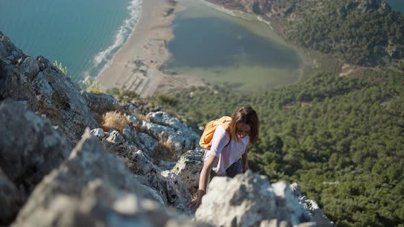 Slow Motion Young Woman Hiker Rock Climber Climbs Up on Cliff on Mountain Over Beautiful Sea Coast