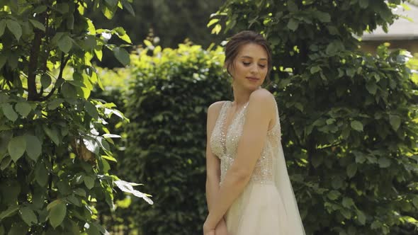 Beautiful and Lovely Bride in Wedding Dress and Veil in the Park Waiting for Groom