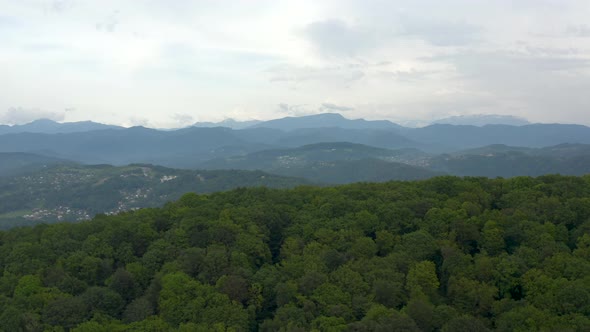 Aerial Shot Raising Up Over Natural Valley Hilly Terrain with City District Landmark Village Houses