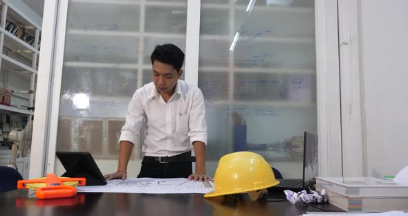 Asian Architect Looking At Blueprint