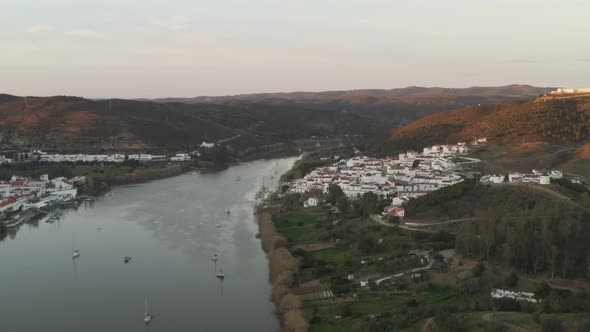 Aerial drone view of Sanlucar de Guadiana in Spain and Alcoutim in Portugal with sail boats on Guadi