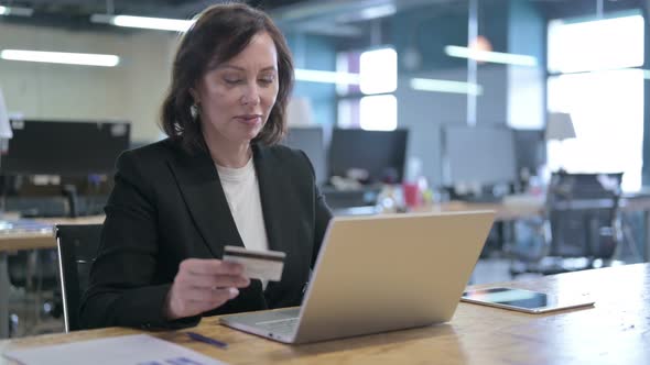Serious Middle Aged Businesswoman Making Online Payment By Credit Card on Laptop