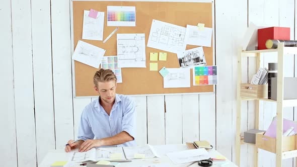 Successful Architector Looking Through Drawings Sitting at Workplace Slow Motion