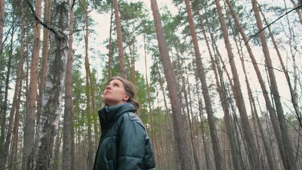 Beautiful young woman walks through green forest