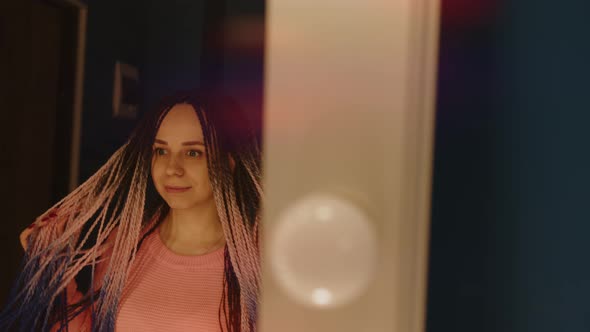 Smiling Young Woman with Dreadlocks Looking at Mirror