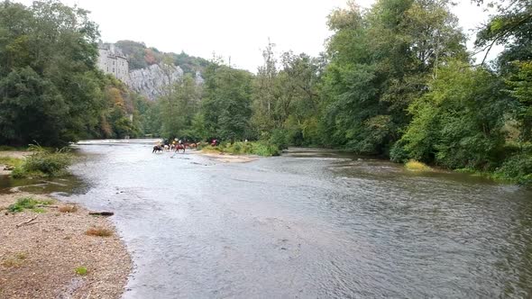 Flying over a river Towards a group of horseback riders with a castle in the background