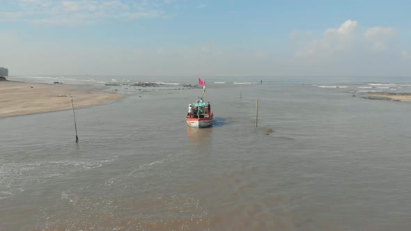 Drone shot of small colourful Indian fishing boat leaving a beach dock