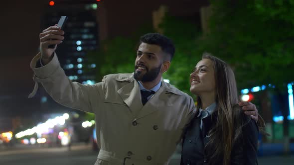 Arabian man and Caucasian woman taking selfie photo with smartphone