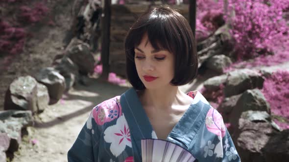 Portrait of Caucasian Woman Dressed Like Japanese Geisha Standing Outdoors on Sakura Trees