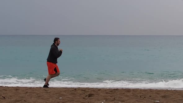 Athletic Man Jogging Through Coast with Beautiful Seascape at Background.