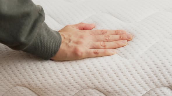 Hand touching and pressing orthopedic mattress