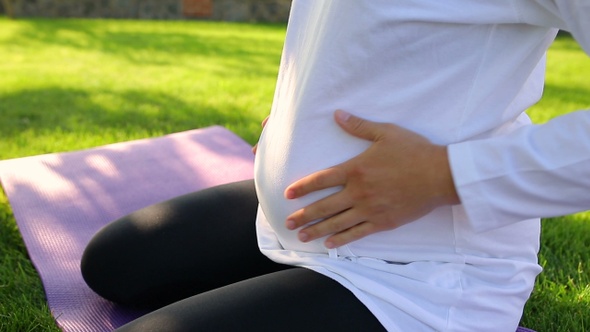 Close-up of pragnant woman on the grass alt
