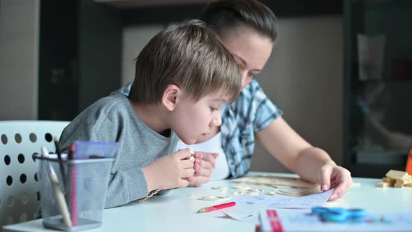 Mom helps her son make a wooden toy from a construction set