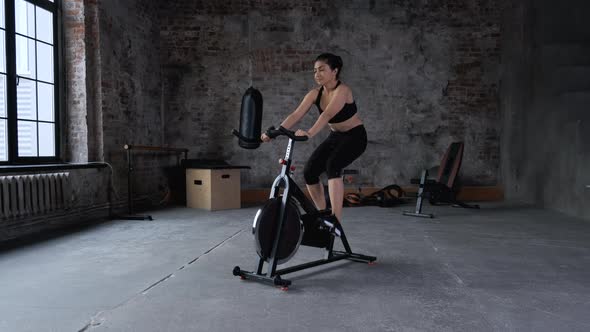 adult Indian woman training on indoor bike while cycling class in gym. Fitness woman spinning bike.