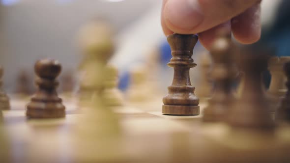 Hesitant hand tries toe chess king and then gives up, close-up