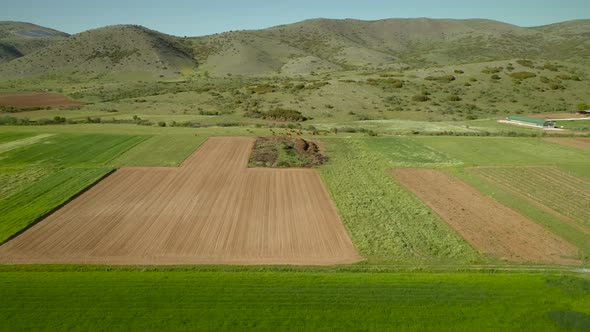 Aerial view of grass fields surrounded by vegetation and hills.