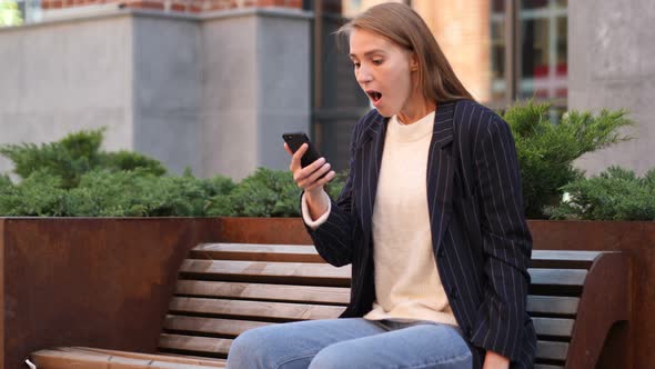 Businesswoman in Shock Reacting to Results on Smartphone