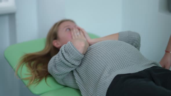 Closeup Pregnant Tummy of Young Caucasian Stressed Woman Lying on Examination Couch Covering Face