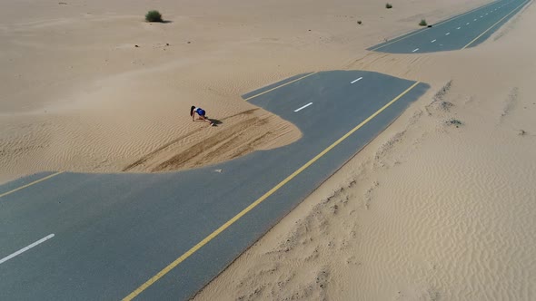 Aerial view of woman doing exercise in road cover by sand on Abu Dhabi, U.A.E