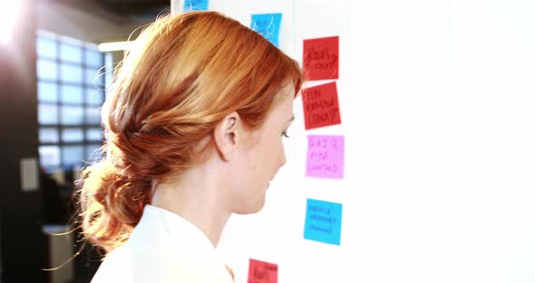 Woman putting sticky notes on whiteboard