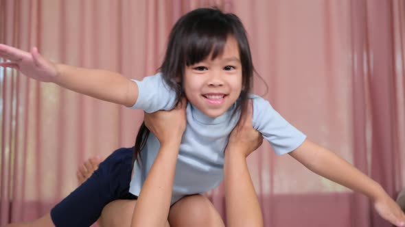 Happy children playing with mom at home. Mother lies on the warm floor and lifts up her little