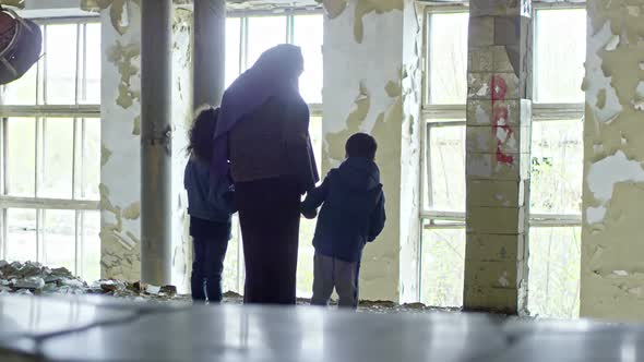 Muslim Woman with Children in Abandoned Building