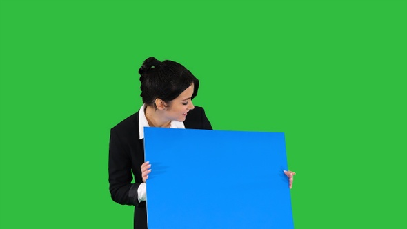 A stylish woman dancing and holding empty poster on a Green