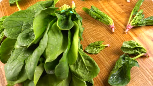 Spinach leaves on a wooden cutting board.