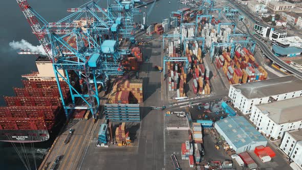 Aerial dolly in of a container cargo ship docked in Valparaiso Sea Port near cranes ready to be load