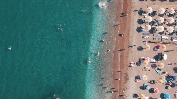 Aerial Top View of Beach with Sunshade and People Swimming at Beautiful Blue Color Sea