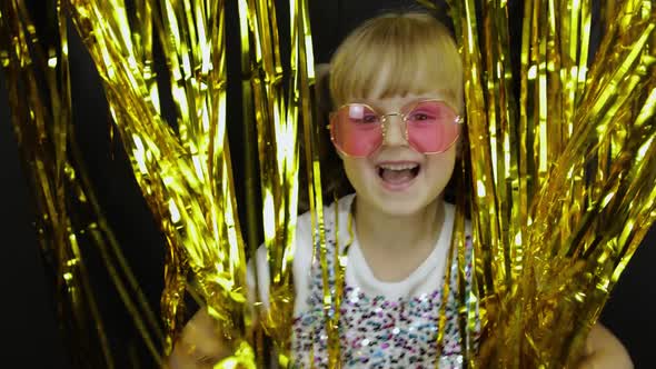 Happy Child Jumping, Playing, Fooling Around in Shiny Foil Fringe Golden Curtain. Little Blonde Kid