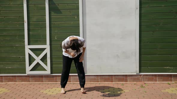 Woman is Practicing Hip Hop and Dancehall Movements Outdoors at Summertime