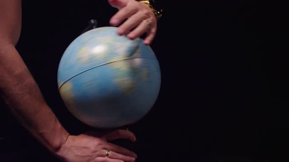 Man rotates the globe on a black background. 