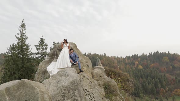 Newlyweds Stand on a High Slope of the Mountain. Groom and Bride